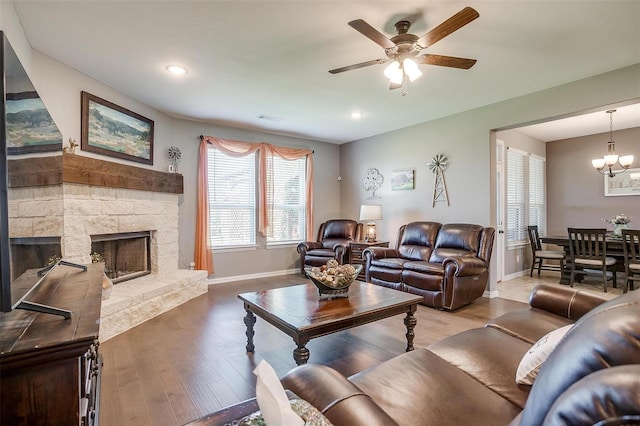 living room featuring a fireplace, hardwood / wood-style floors, and ceiling fan with notable chandelier