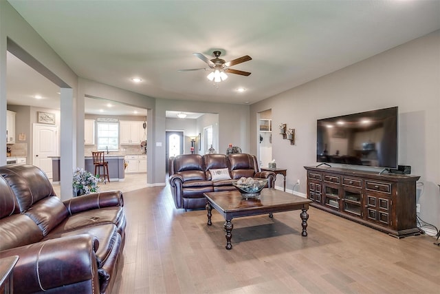 living room with ceiling fan, light hardwood / wood-style floors, and sink