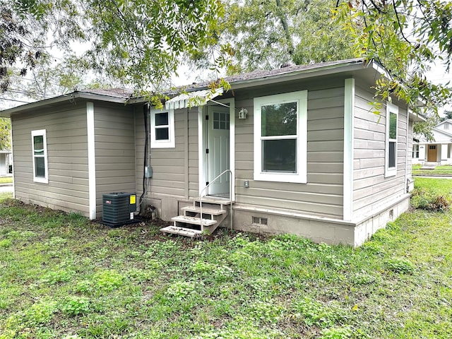 rear view of property with entry steps, crawl space, cooling unit, and a yard