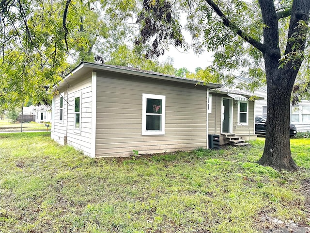 view of side of home with entry steps, central AC, and a lawn