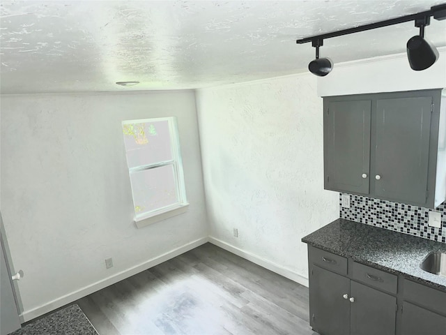 kitchen featuring backsplash, gray cabinets, a textured ceiling, and track lighting