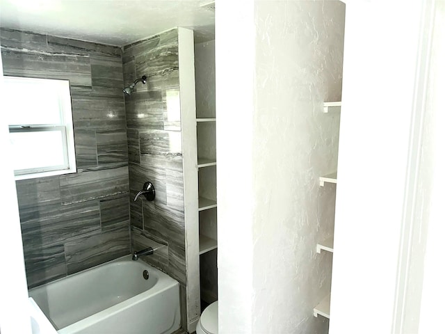 bathroom featuring tiled shower / bath combo and toilet