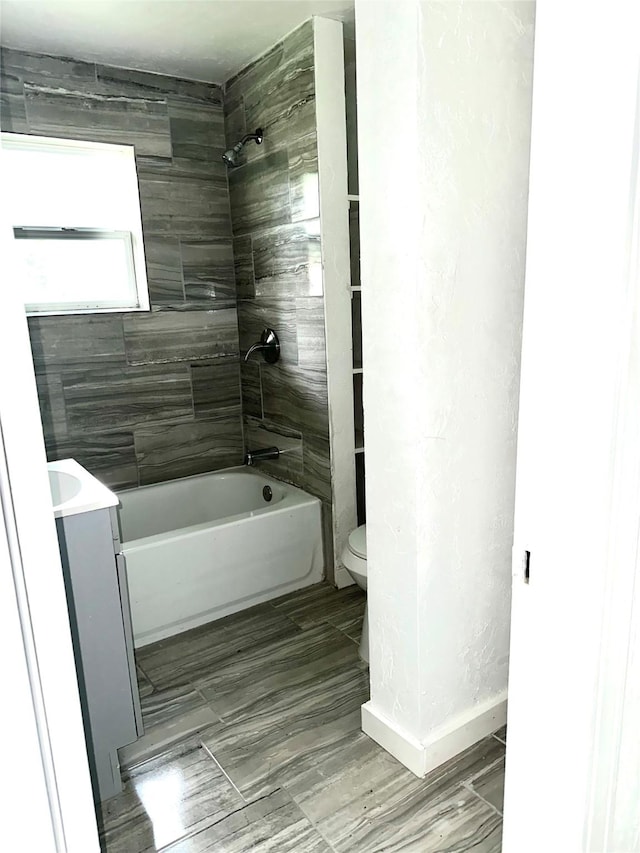 full bathroom with vanity, tiled shower / bath combo, and toilet