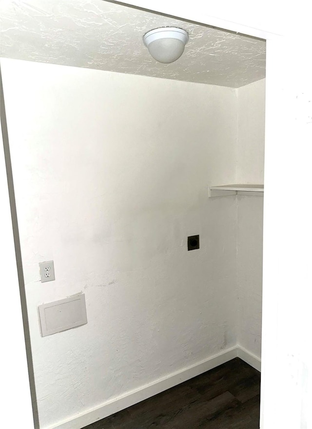 clothes washing area with hookup for an electric dryer, a textured ceiling, and dark wood-type flooring