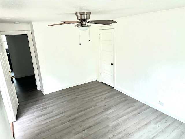 empty room with ceiling fan, baseboards, and wood finished floors