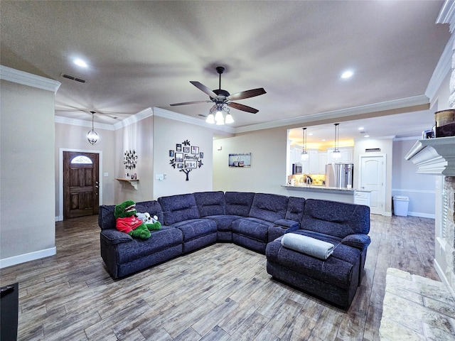 living room featuring ceiling fan, a stone fireplace, and ornamental molding