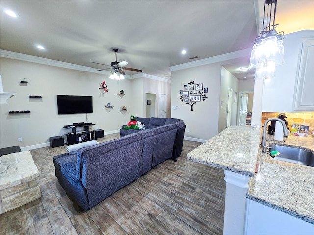 living room featuring dark hardwood / wood-style floors, ceiling fan, crown molding, and sink