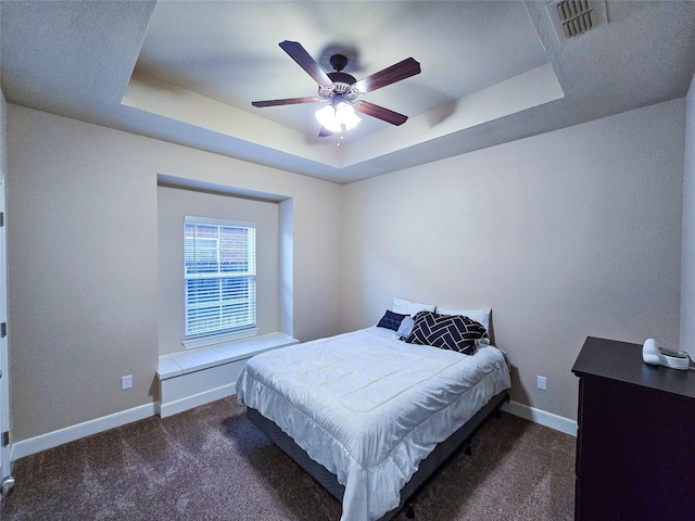 carpeted bedroom featuring a raised ceiling and ceiling fan