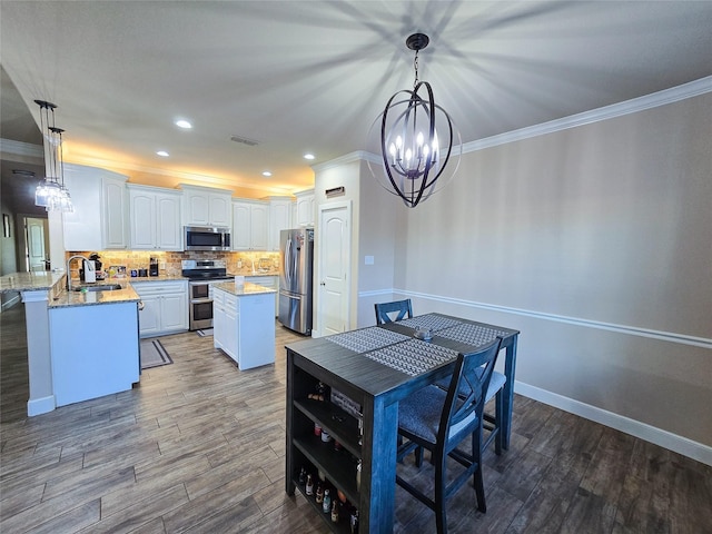 dining area featuring ornamental molding, sink, light hardwood / wood-style floors, and a notable chandelier