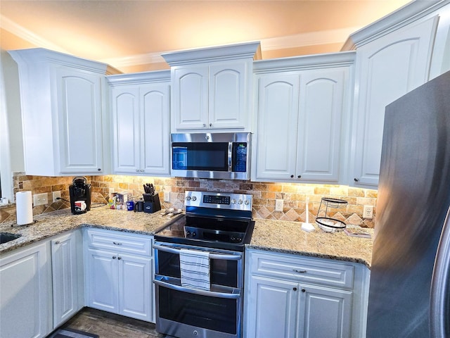 kitchen with light stone countertops, white cabinetry, stainless steel appliances, backsplash, and crown molding