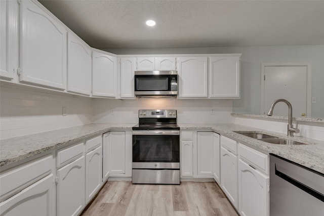 kitchen with light stone countertops, sink, white cabinets, and appliances with stainless steel finishes