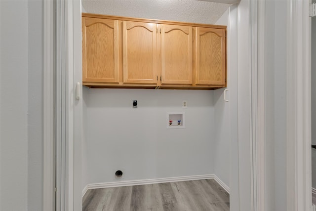 washroom with cabinets, washer hookup, light wood-type flooring, a textured ceiling, and hookup for an electric dryer