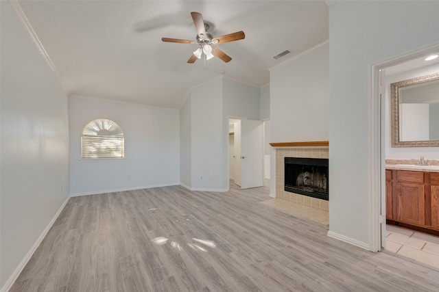 unfurnished living room featuring a tile fireplace, light wood-type flooring, ceiling fan, and crown molding