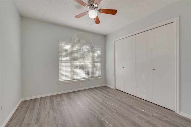 unfurnished bedroom featuring ceiling fan, a closet, light hardwood / wood-style floors, and a textured ceiling