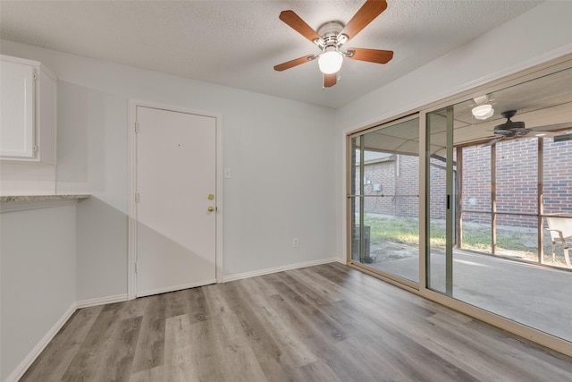 empty room with a textured ceiling, light hardwood / wood-style floors, and ceiling fan