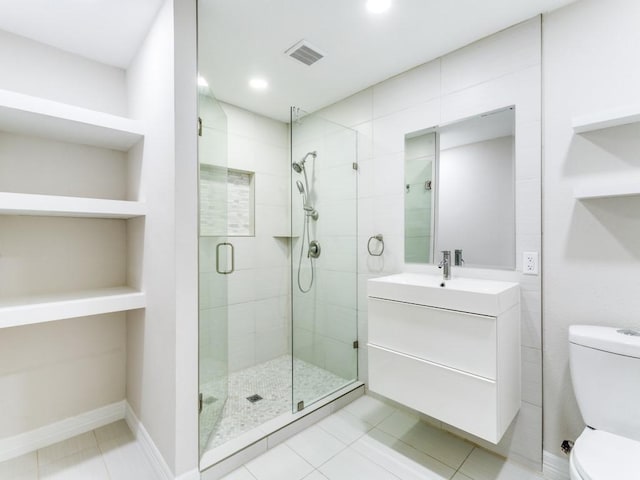 bathroom with tile patterned floors, vanity, toilet, and a shower with shower door