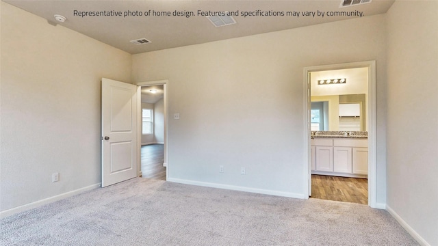 unfurnished bedroom featuring connected bathroom and light colored carpet