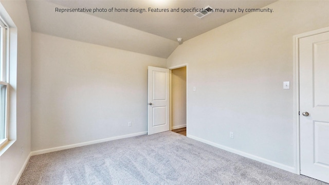 carpeted spare room featuring vaulted ceiling