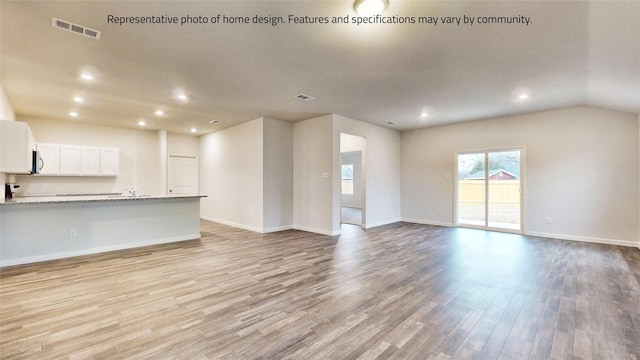 unfurnished living room featuring light hardwood / wood-style floors and vaulted ceiling