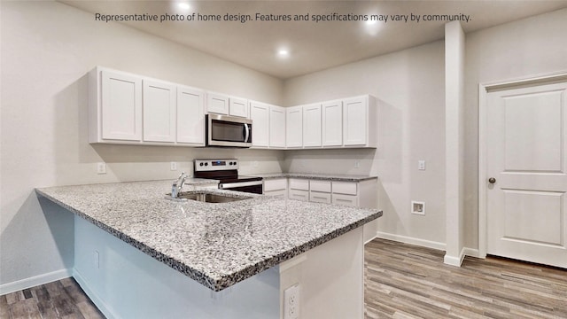 kitchen with kitchen peninsula, appliances with stainless steel finishes, and white cabinetry