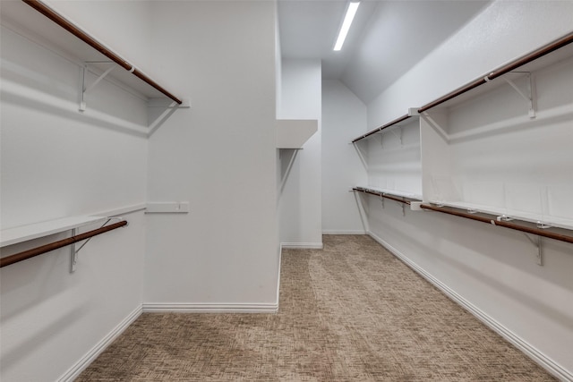 spacious closet with vaulted ceiling and light colored carpet