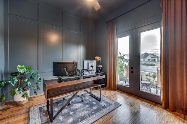 office with light wood-type flooring and french doors