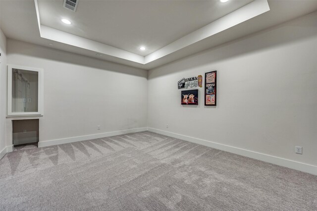 carpeted spare room with a raised ceiling