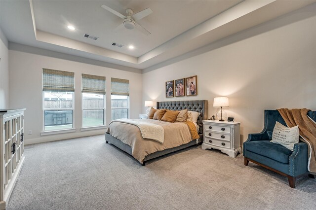 carpeted bedroom featuring a tray ceiling and ceiling fan