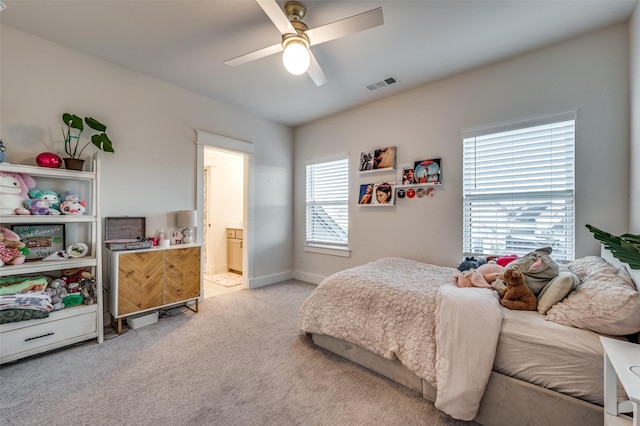 carpeted bedroom with ceiling fan and ensuite bath