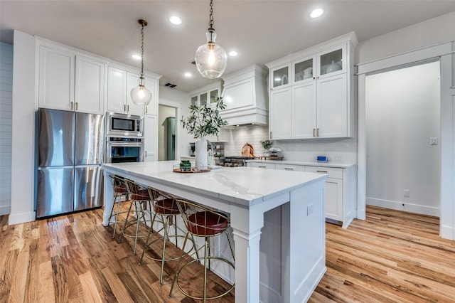 kitchen with pendant lighting, a center island, white cabinets, decorative backsplash, and stainless steel appliances