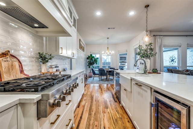 kitchen with beverage cooler, tasteful backsplash, pendant lighting, white cabinets, and custom range hood