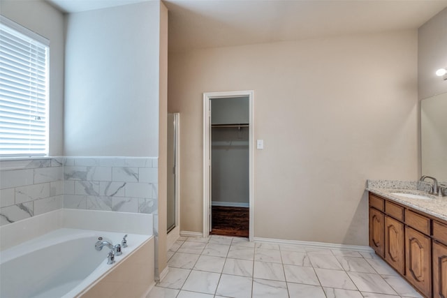 bathroom featuring plus walk in shower, vanity, and a wealth of natural light