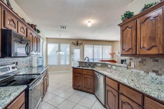 kitchen with light stone countertops, appliances with stainless steel finishes, backsplash, and sink