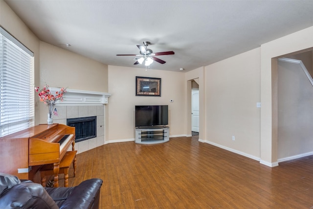 living room featuring ceiling fan, hardwood / wood-style flooring, a wealth of natural light, and a tiled fireplace