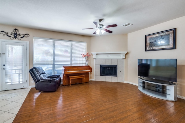 living room with a tile fireplace, hardwood / wood-style floors, and ceiling fan