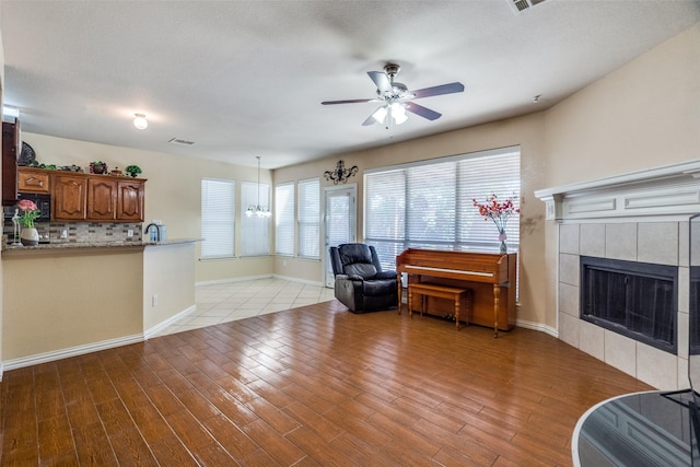 living room with a fireplace and ceiling fan with notable chandelier