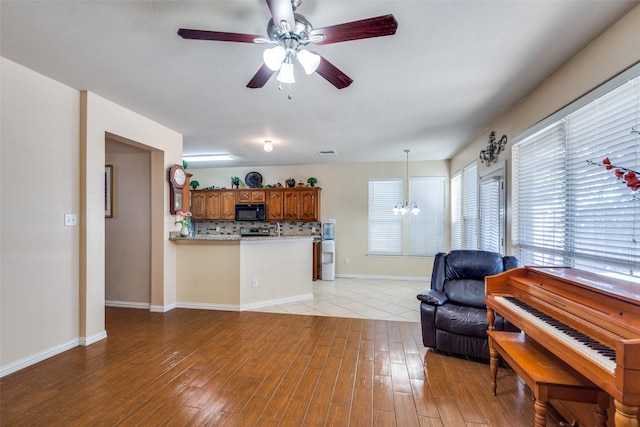 living room featuring ceiling fan with notable chandelier and light hardwood / wood-style flooring