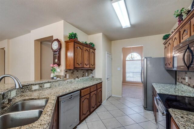 kitchen featuring sink, light stone counters, decorative backsplash, light tile patterned flooring, and appliances with stainless steel finishes