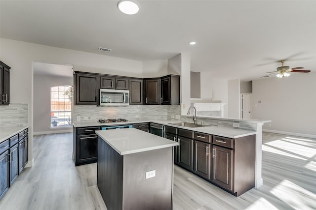 kitchen with ceiling fan, sink, a center island, light hardwood / wood-style flooring, and appliances with stainless steel finishes