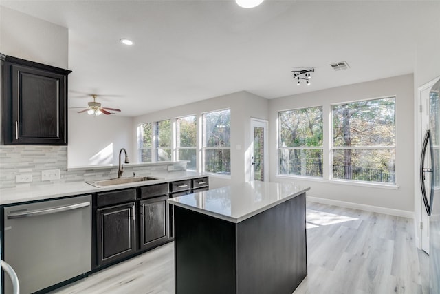 kitchen with decorative backsplash, stainless steel dishwasher, a wealth of natural light, sink, and a center island