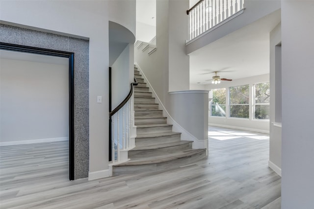 staircase with hardwood / wood-style floors and ceiling fan