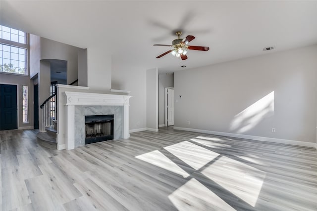 unfurnished living room with ceiling fan, light wood-type flooring, and a fireplace