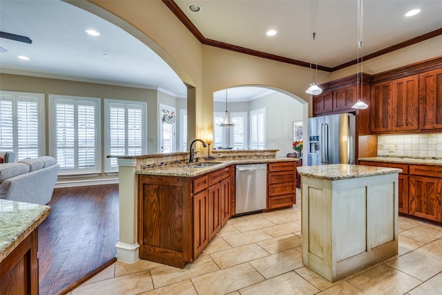 kitchen with sink, stainless steel appliances, backsplash, pendant lighting, and a kitchen island with sink