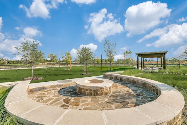 view of property's community featuring an outdoor fire pit, a patio area, and a lawn