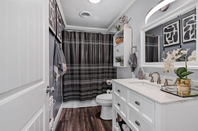 bathroom with ornamental molding, vanity, a textured ceiling, hardwood / wood-style floors, and toilet