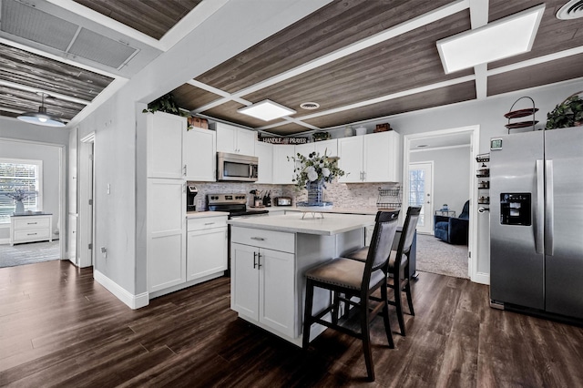 kitchen featuring a center island, wooden ceiling, appliances with stainless steel finishes, tasteful backsplash, and white cabinetry