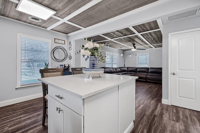 kitchen featuring ceiling fan, a kitchen island, a kitchen breakfast bar, dark hardwood / wood-style floors, and white cabinets