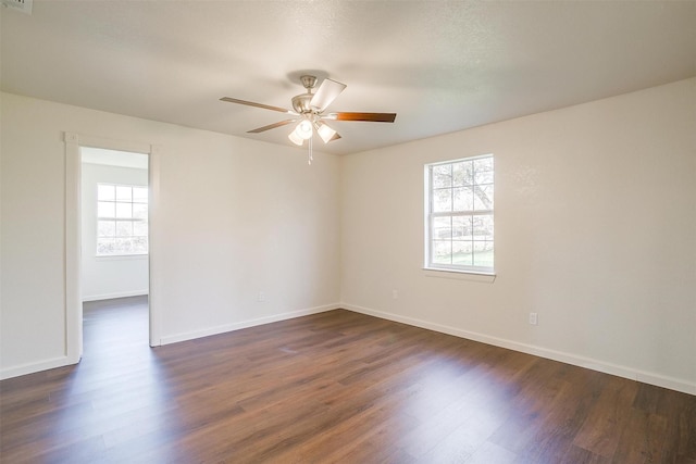 spare room with dark hardwood / wood-style floors, ceiling fan, and a wealth of natural light