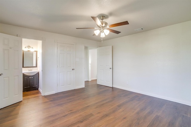 unfurnished bedroom featuring ensuite bathroom, dark hardwood / wood-style flooring, ceiling fan, and sink