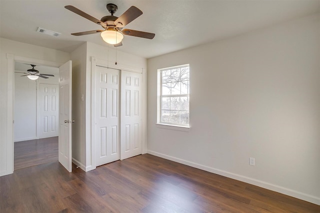 unfurnished bedroom with ceiling fan, dark hardwood / wood-style floors, and a closet